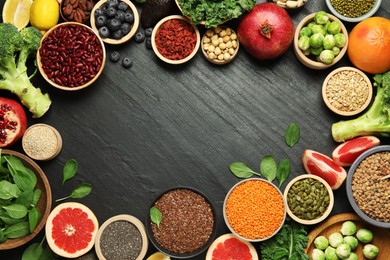 Photo of Frame of different superfood products on black table, flat lay. Space for text