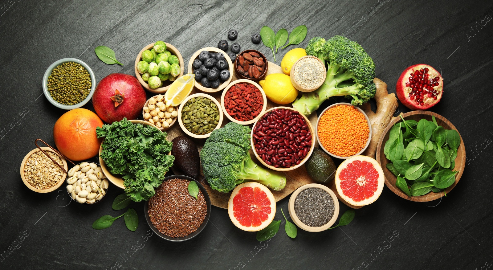 Photo of Different superfood products on black table, flat lay