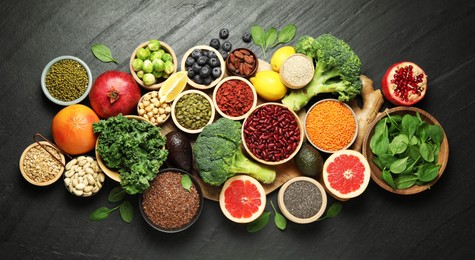 Photo of Different superfood products on black table, flat lay