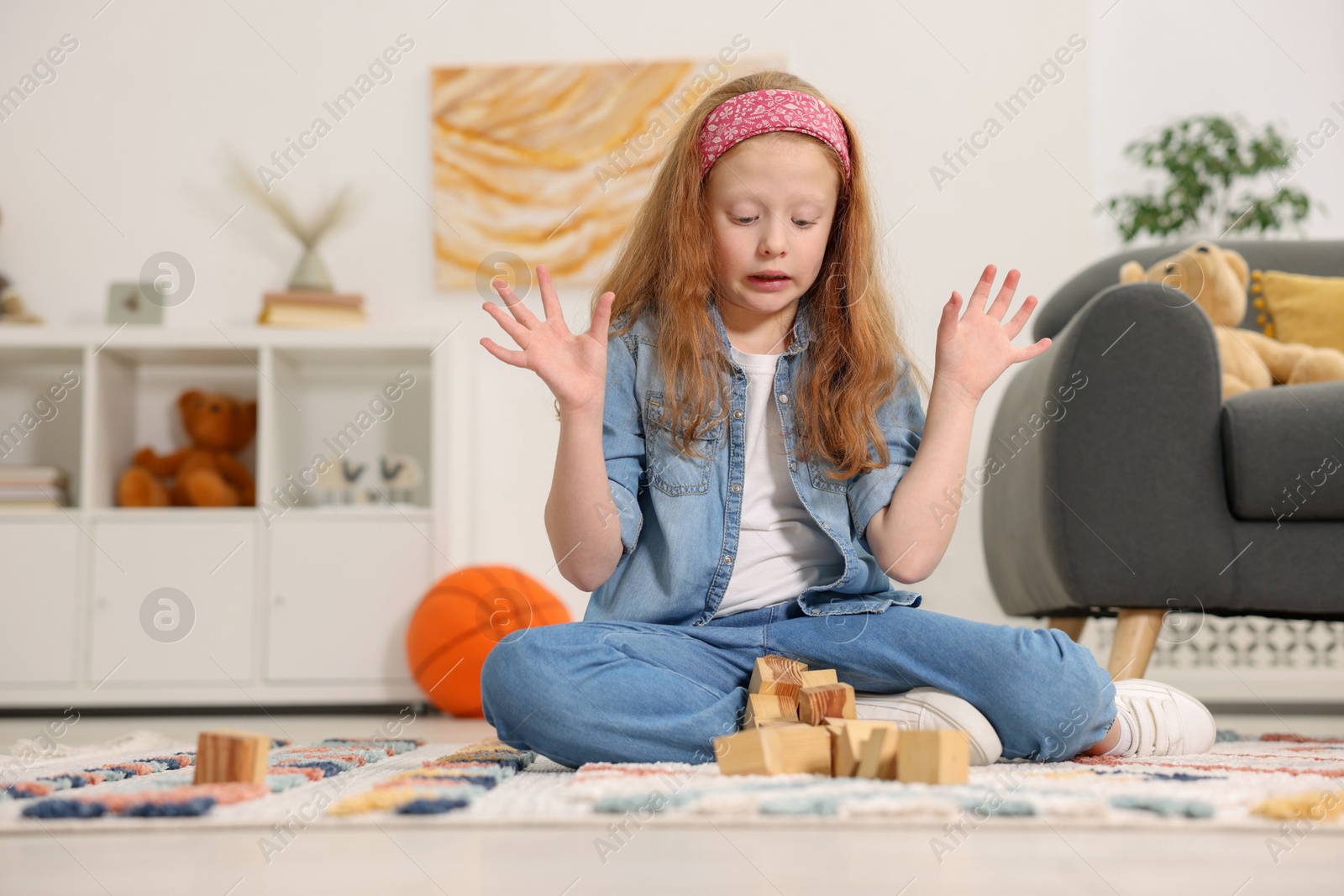 Photo of Little girl playing with wooden cubes on floor indoors, space for text