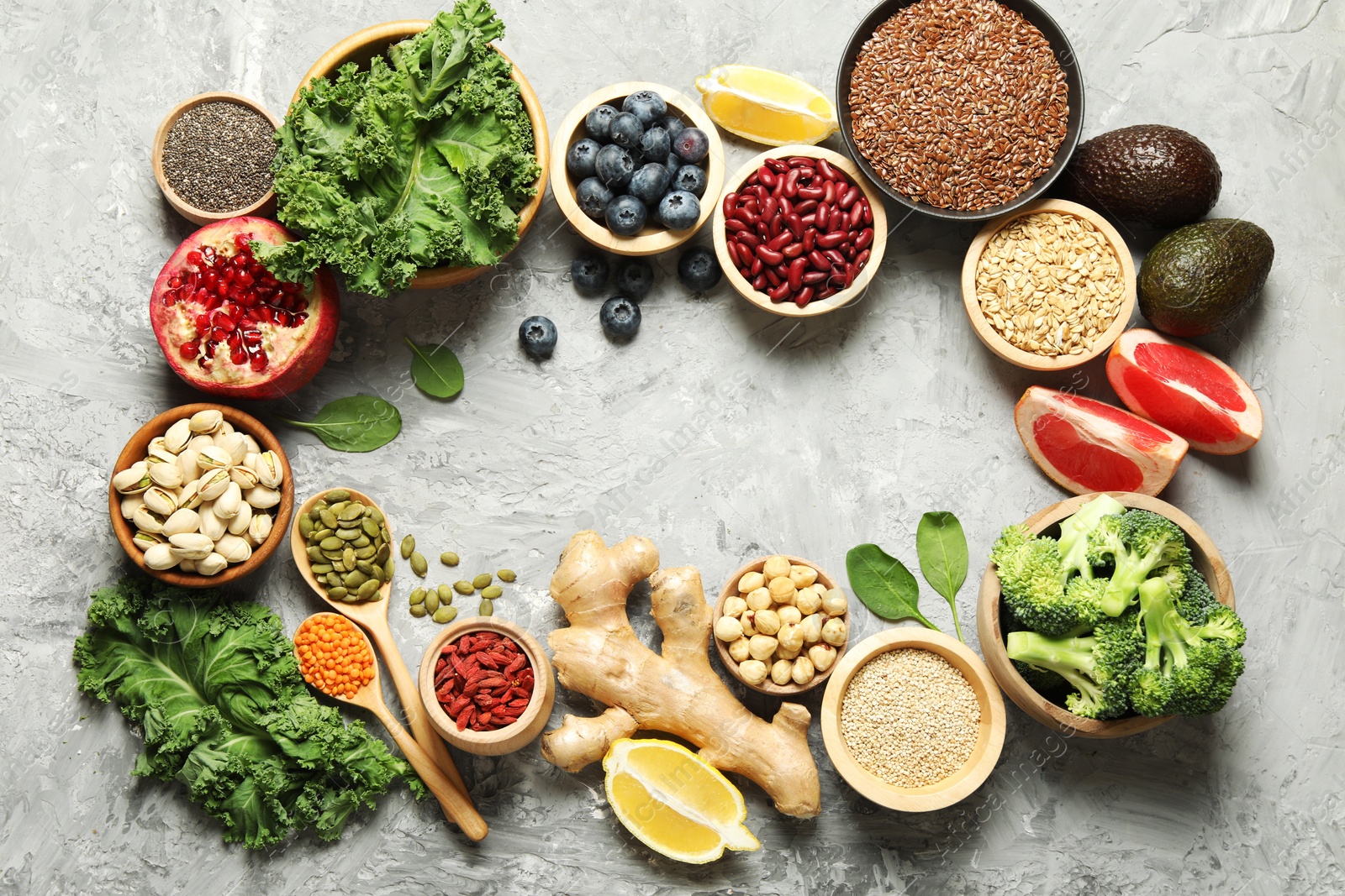 Photo of Frame of different superfood products on grey table, flat lay. Space for text