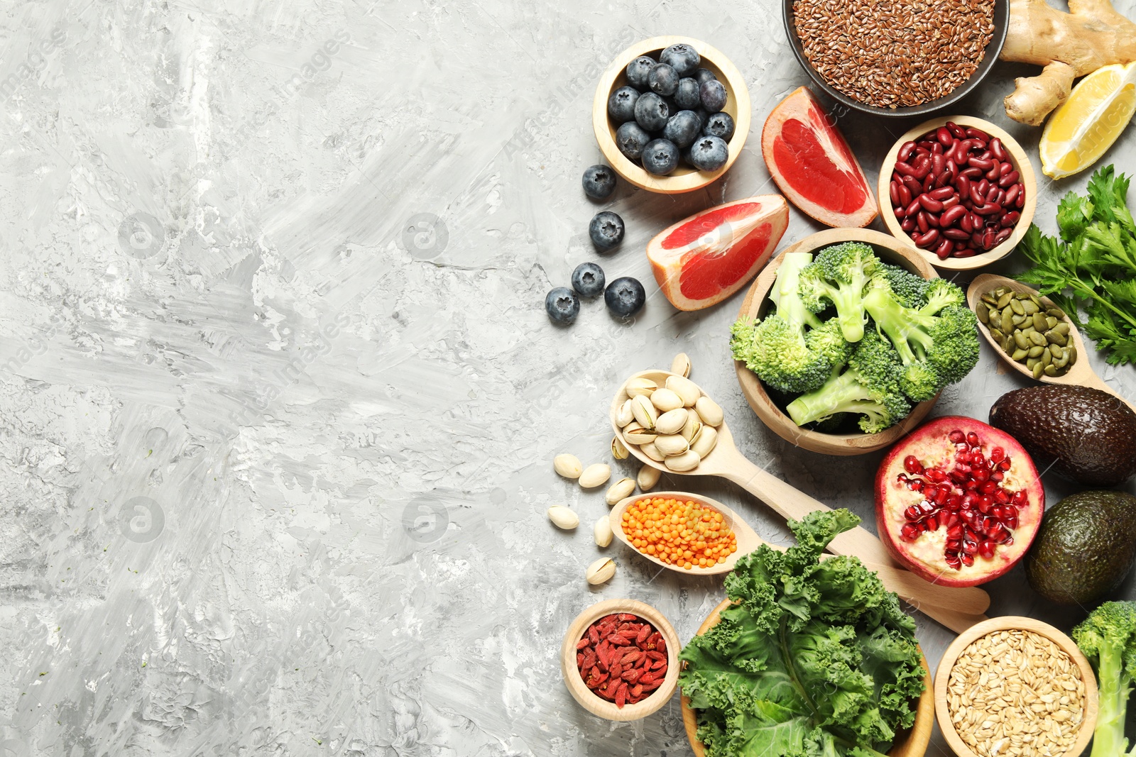 Photo of Different superfood products on grey table, flat lay. Space for text