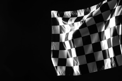 Photo of One racing checkered flag on black background, space for text