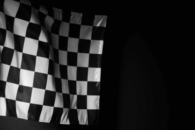 Photo of One racing checkered flag on black background, space for text