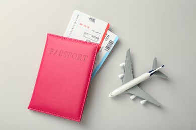 Photo of Passport with tickets and plane model on light background, top view