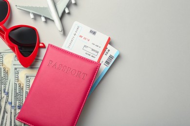 Photo of Passport with tickets, plane model, money and sunglasses on light background, flat lay. Space for text