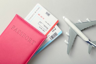 Photo of Passport with tickets and plane model on light background, top view