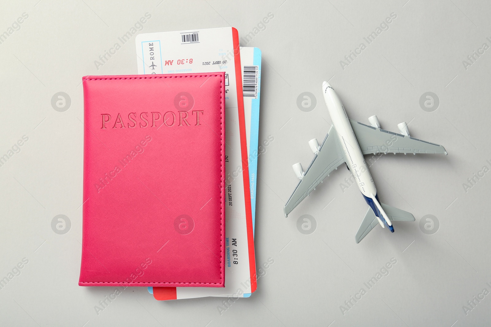 Photo of Passport with tickets and plane model on light background, top view