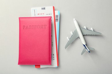 Photo of Passport with tickets and plane model on light background, top view