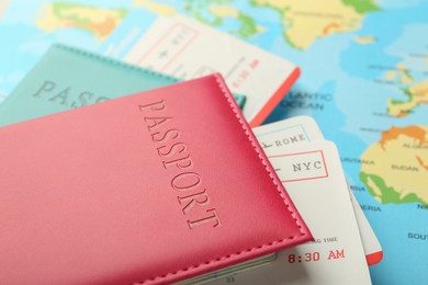 Photo of Passports in color covers and flight tickets on world map, closeup