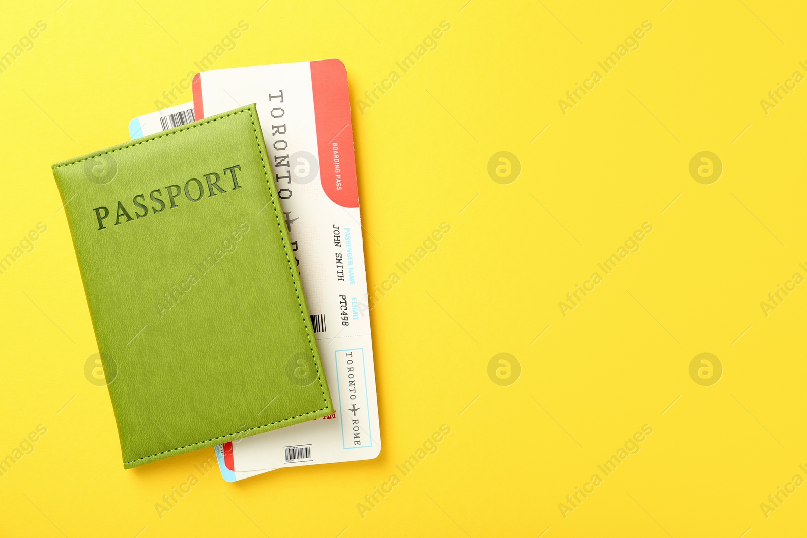 Photo of Passport with tickets on yellow background, top view. Space for text