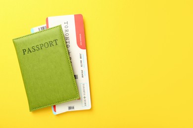 Photo of Passport with tickets on yellow background, top view. Space for text