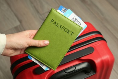 Photo of Woman with passport, tickets and suitcase indoors, closeup