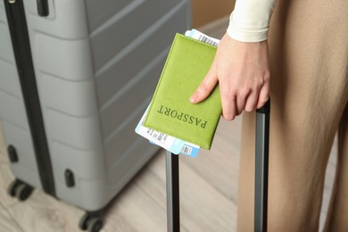 Photo of Woman with passport, tickets and suitcases indoors, closeup