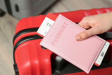 Photo of Woman with passport, ticket and suitcase indoors, closeup