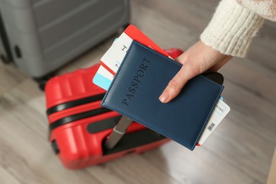 Photo of Woman with passport, tickets and suitcases indoors, closeup