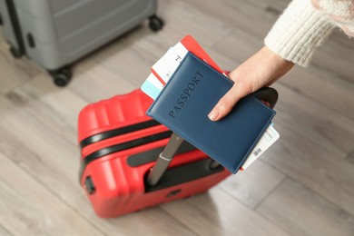 Photo of Woman with passport, tickets and suitcases indoors, closeup