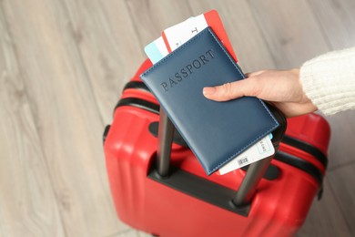 Photo of Woman with passport, tickets and suitcase indoors, closeup