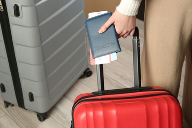 Photo of Woman with passport, tickets and suitcase indoors, closeup