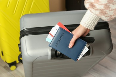 Photo of Woman with passport, tickets and suitcases indoors, closeup