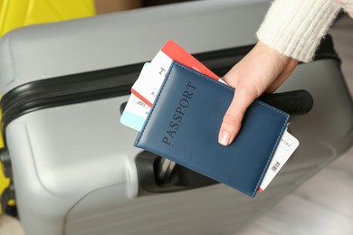 Photo of Woman with passport, tickets and suitcases indoors, closeup