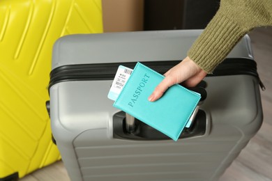 Photo of Woman with passport, ticket and suitcases indoors, closeup