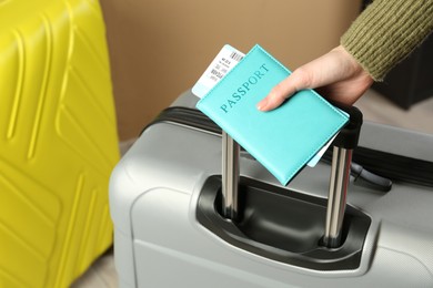 Photo of Woman with passport, ticket and suitcases indoors, closeup