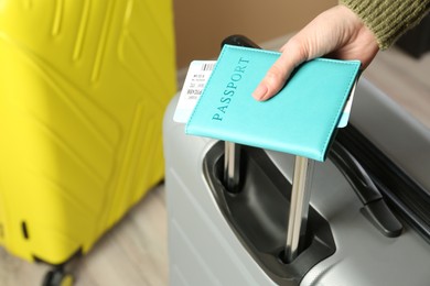 Photo of Woman with passport, ticket and suitcases indoors, closeup