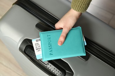 Photo of Woman with passport, ticket and suitcase indoors, closeup