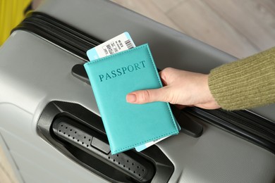 Photo of Woman with passport, ticket and suitcase indoors, closeup