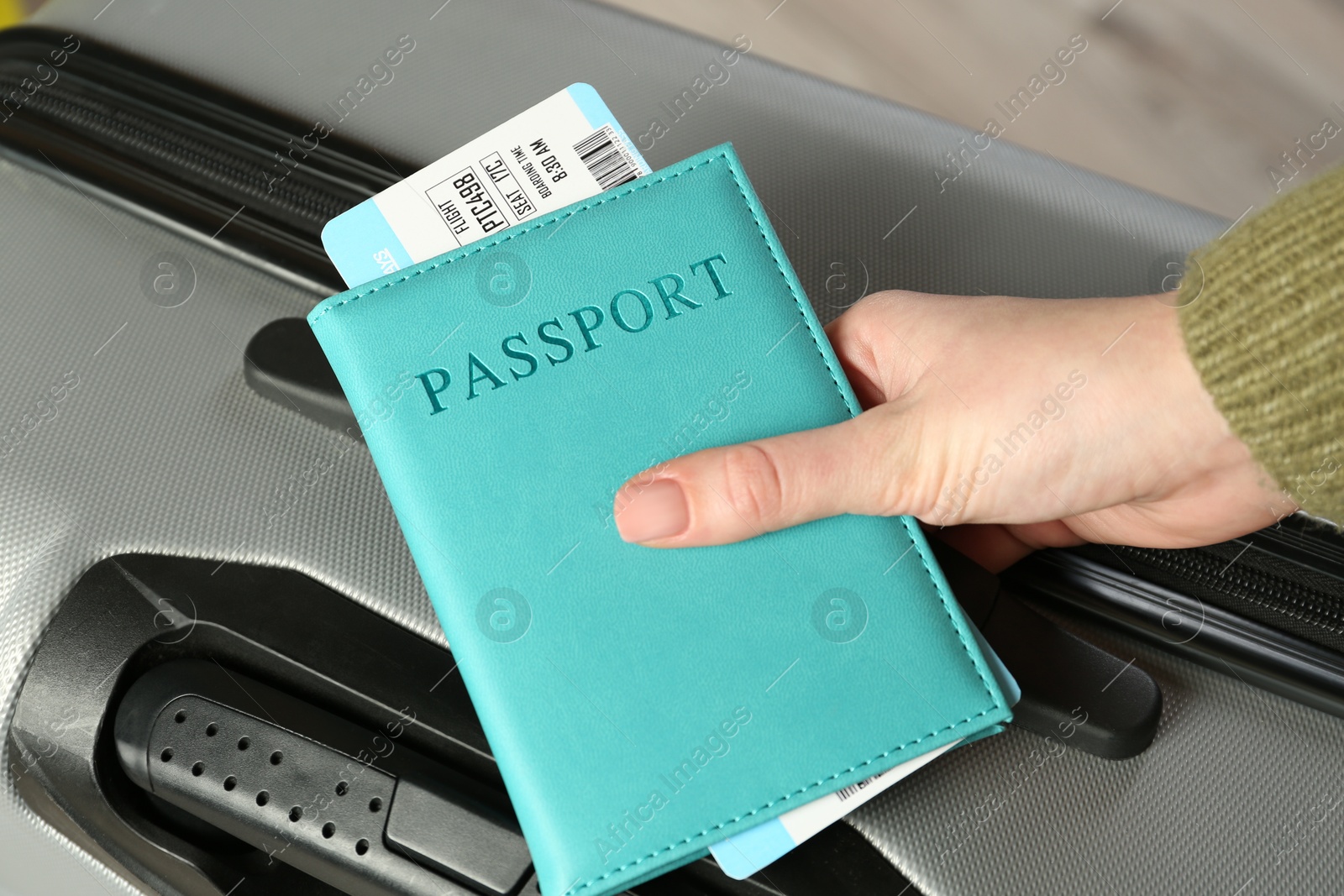 Photo of Woman with passport, ticket and suitcase indoors, closeup