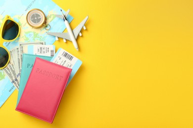 Photo of Passports with tickets, map, money, compass, sunglasses and airplane model on yellow background, flat lay. Space for text