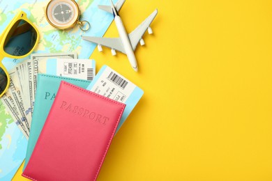 Photo of Passports with tickets, map, money, compass, sunglasses and airplane model on yellow background, flat lay. Space for text