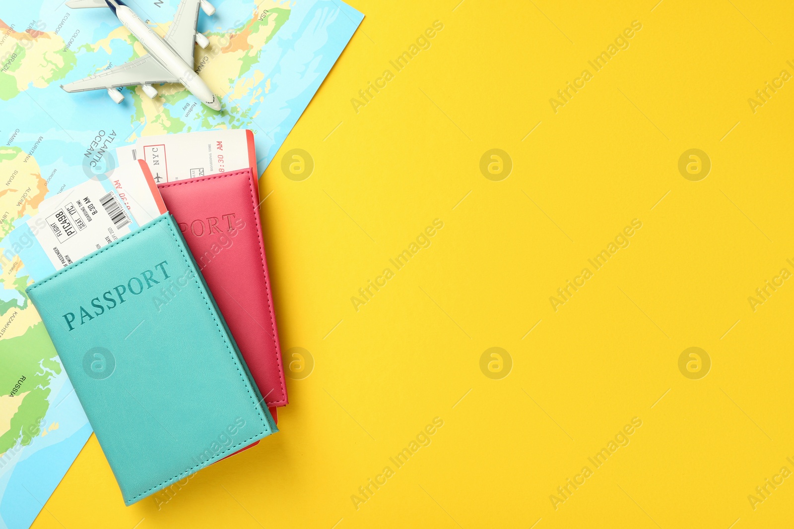 Photo of Passports with tickets, map and airplane model on yellow background, flat lay. Space for text