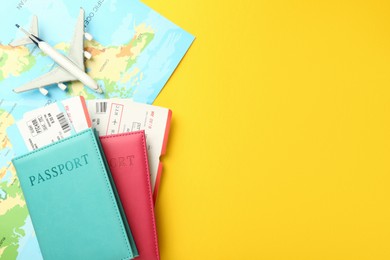 Photo of Passports with tickets, map and airplane model on yellow background, flat lay. Space for text