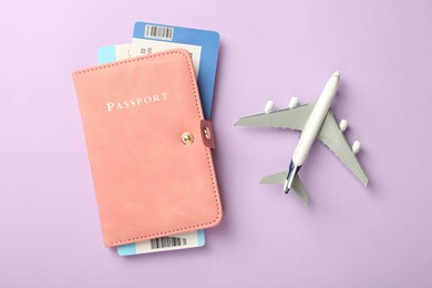 Photo of Passport with tickets and airplane model on lilac background, flat lay