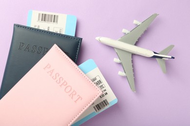 Photo of Passports with tickets and airplane model on lilac background, top view