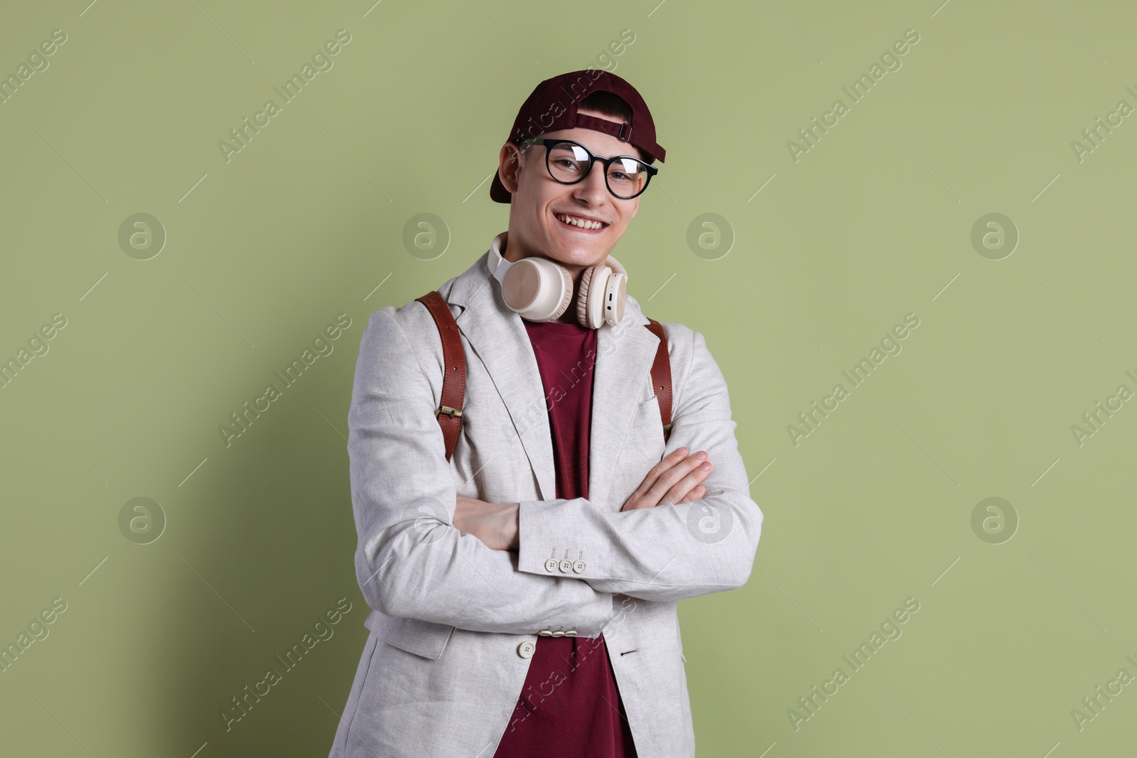 Photo of Student with headphones and backpack on olive background