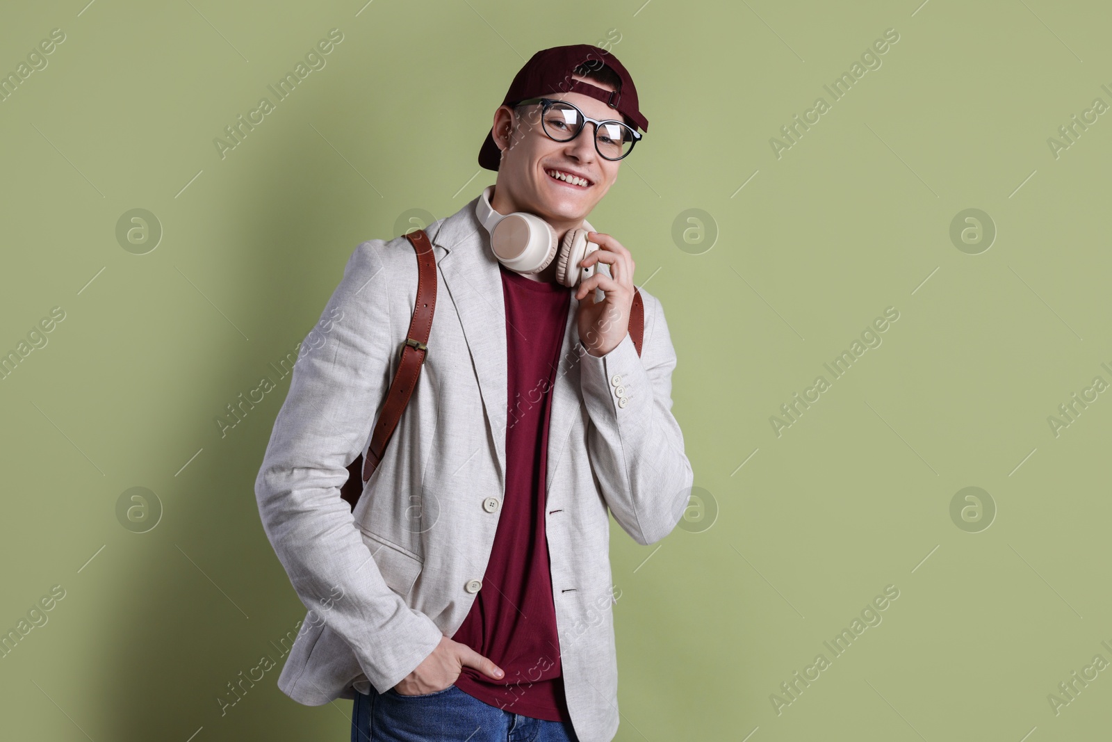 Photo of Student with headphones and backpack on olive background