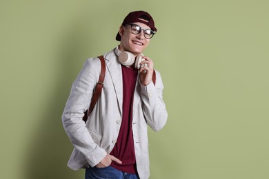 Photo of Student with headphones and backpack on olive background