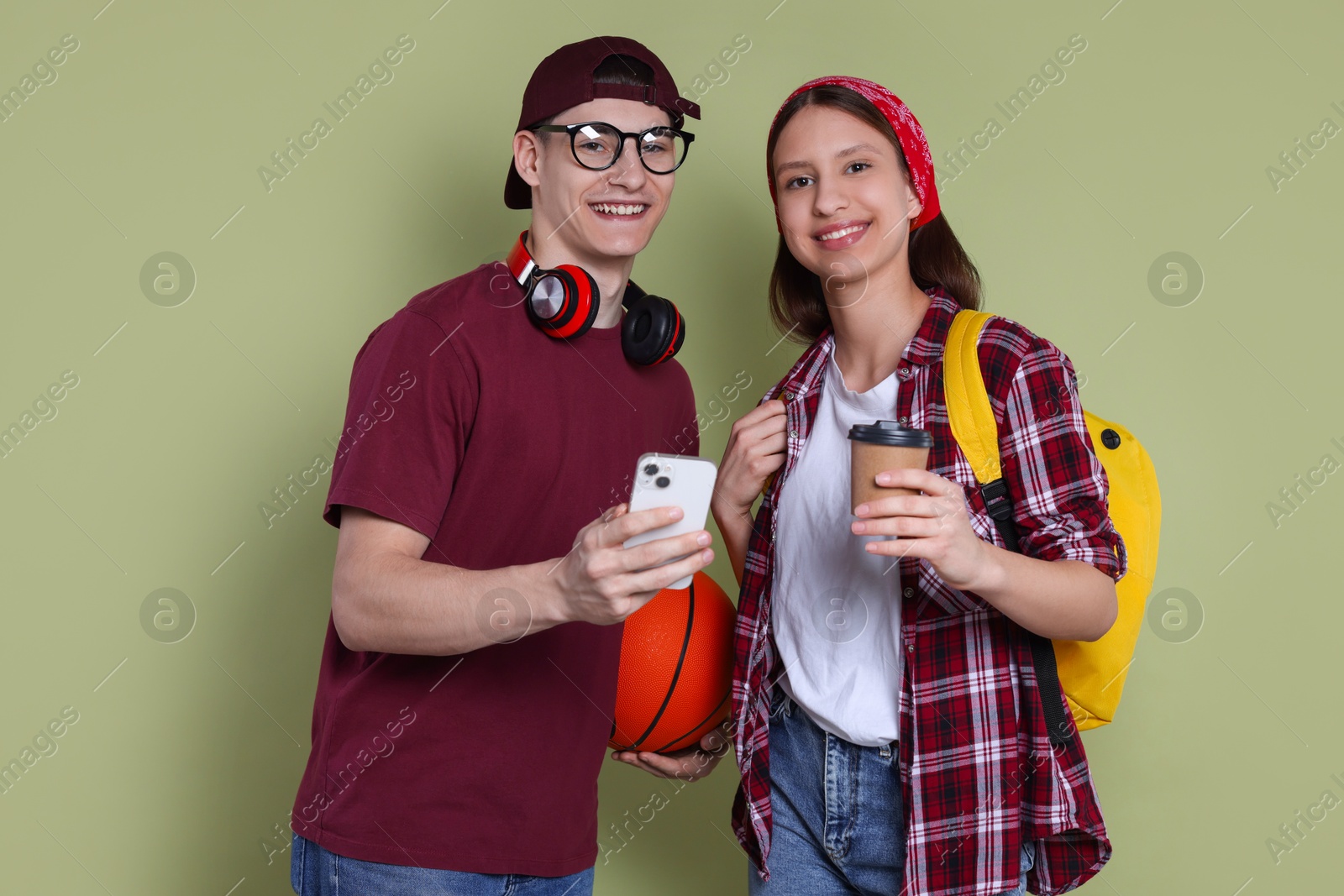 Photo of Student showing something on smartphone to girl against olive background