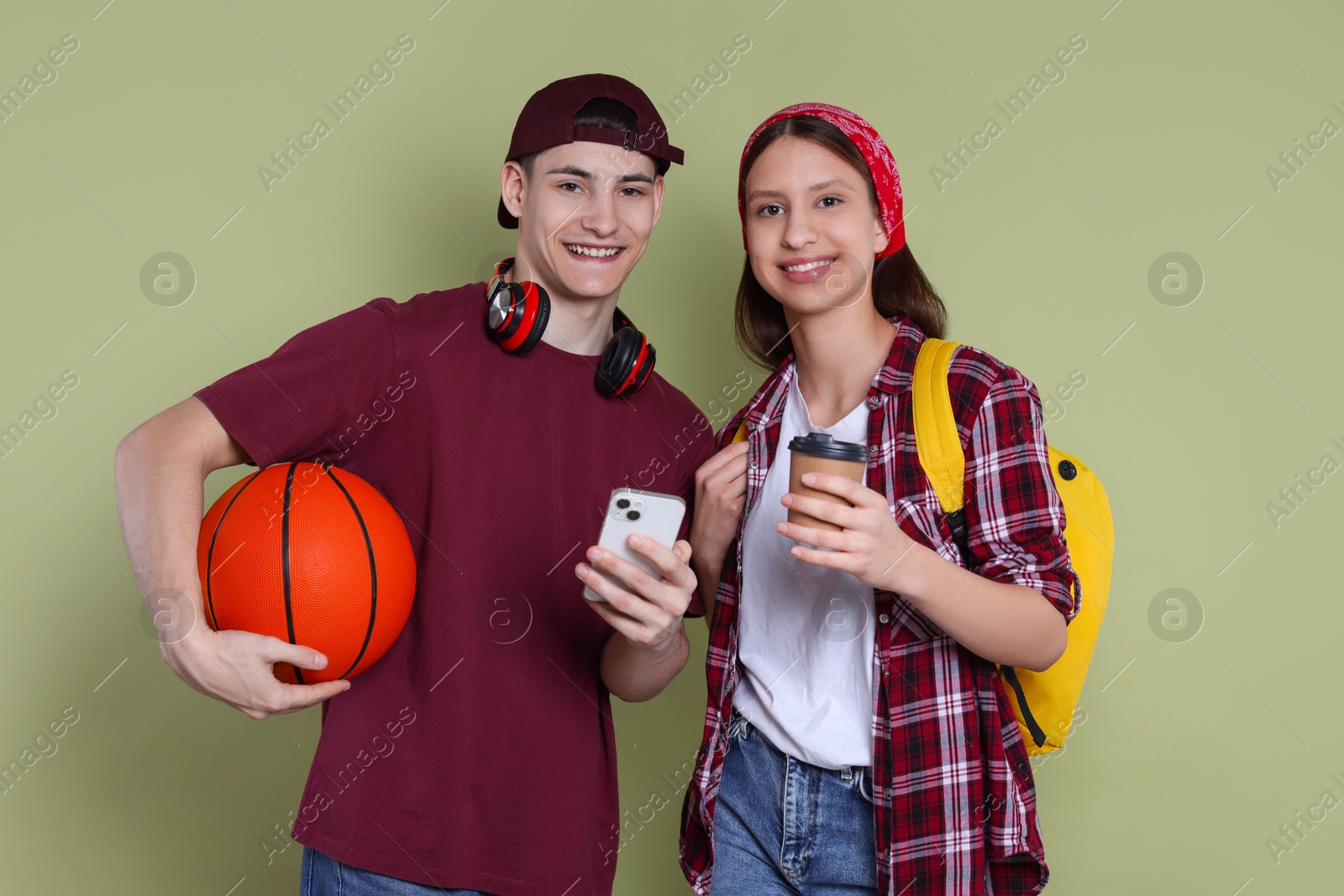 Photo of Students with smartphone, paper cup of coffee and basketball ball on olive background