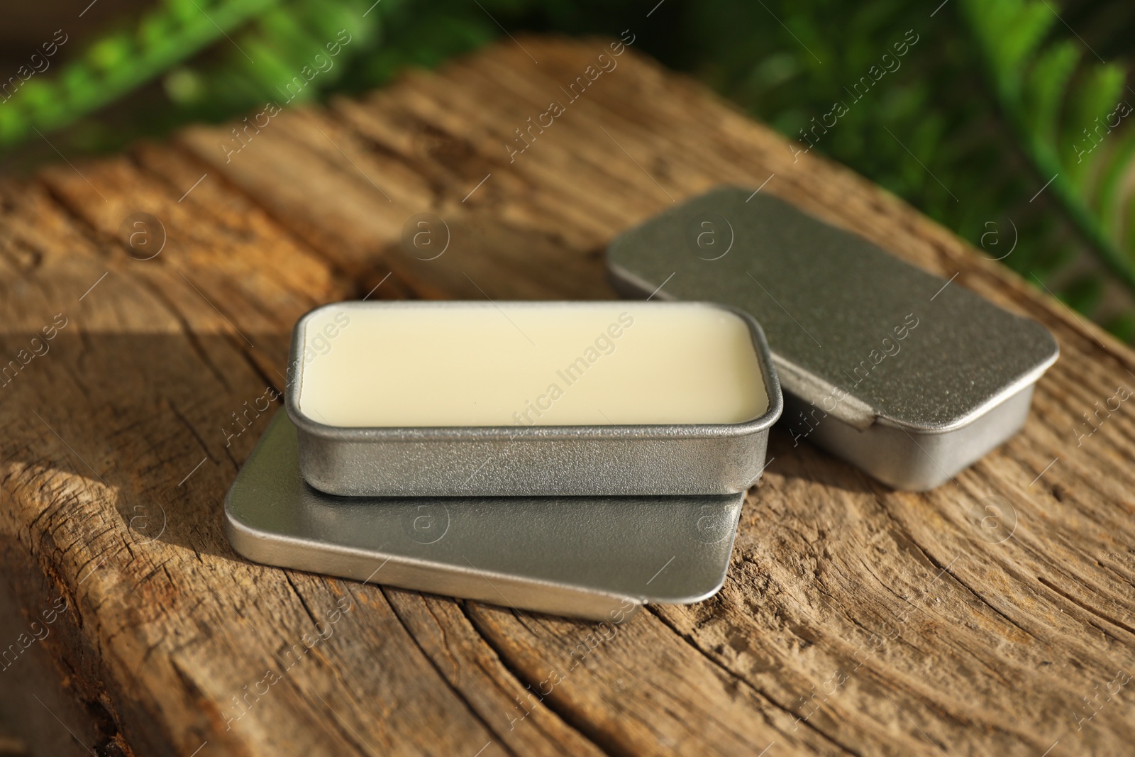 Photo of Natural solid perfume in containers on wood, closeup