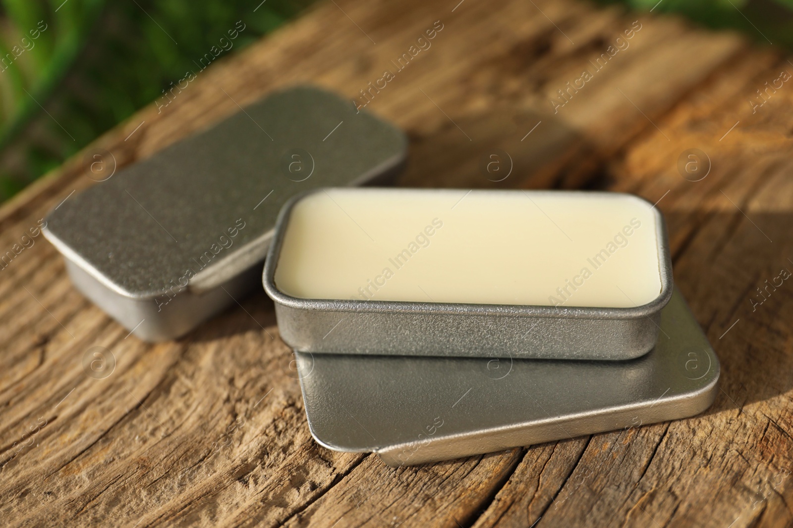 Photo of Natural solid perfume in containers on wood, closeup