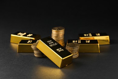 Photo of Gold bars and coins on black table, closeup