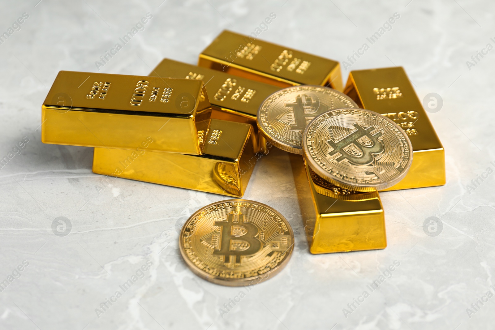 Photo of Gold bars and coins on grey marble table, closeup