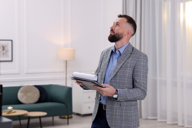 Photo of Real estate appraisal. Inspector with clipboard conducting property valuation indoors, space for text