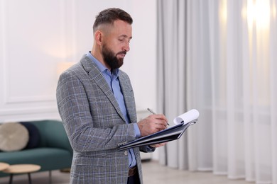 Photo of Real estate appraisal. Inspector with clipboard conducting property valuation indoors, space for text