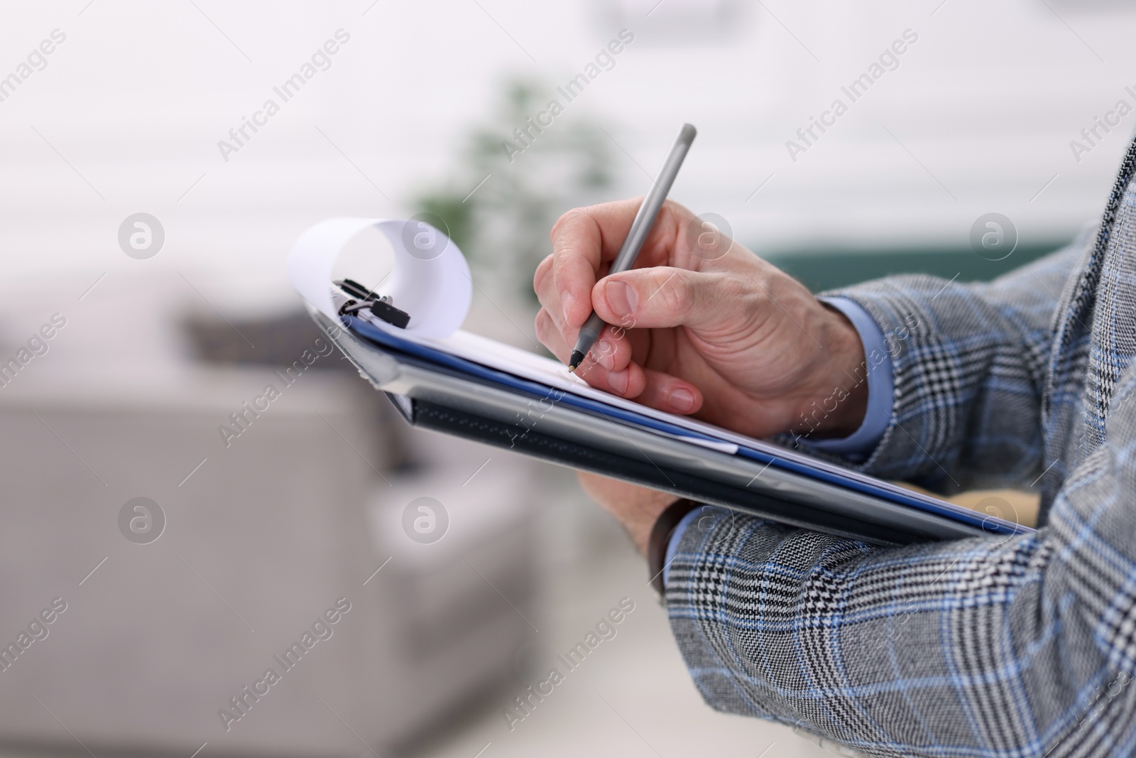 Photo of Real estate appraisal. Inspector with clipboard conducting property valuation indoors, closeup. Space for text