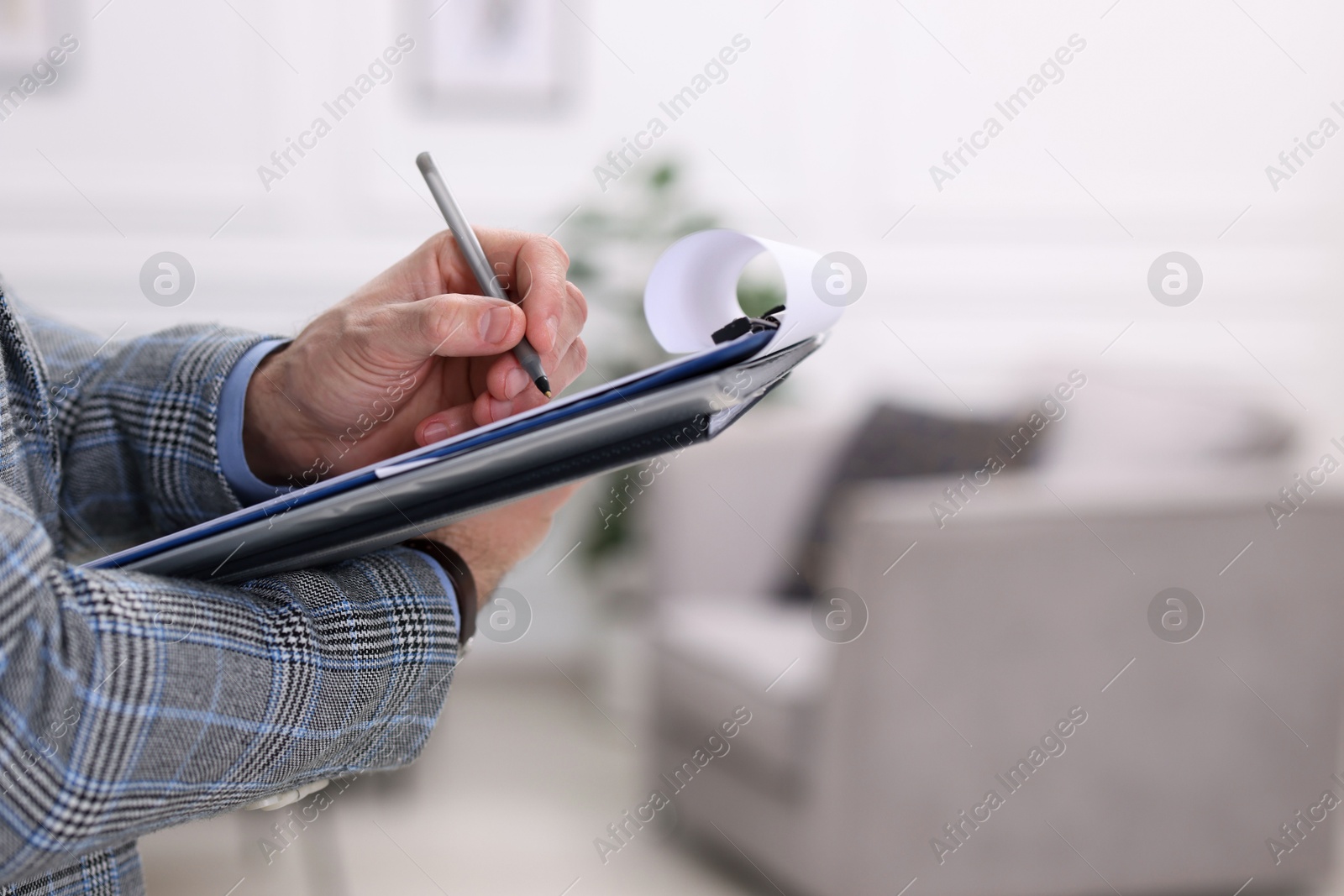 Photo of Real estate appraisal. Inspector with clipboard conducting property valuation indoors, closeup. Space for text